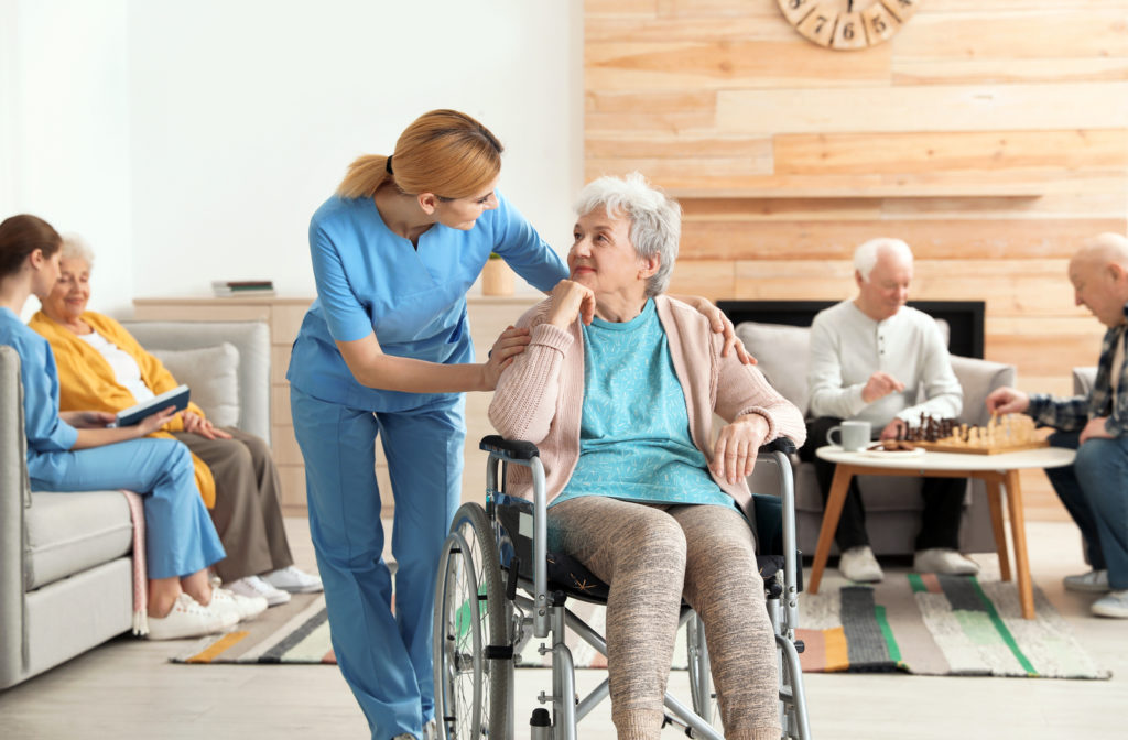 Nurse helping senior women in wheelchair across senior community