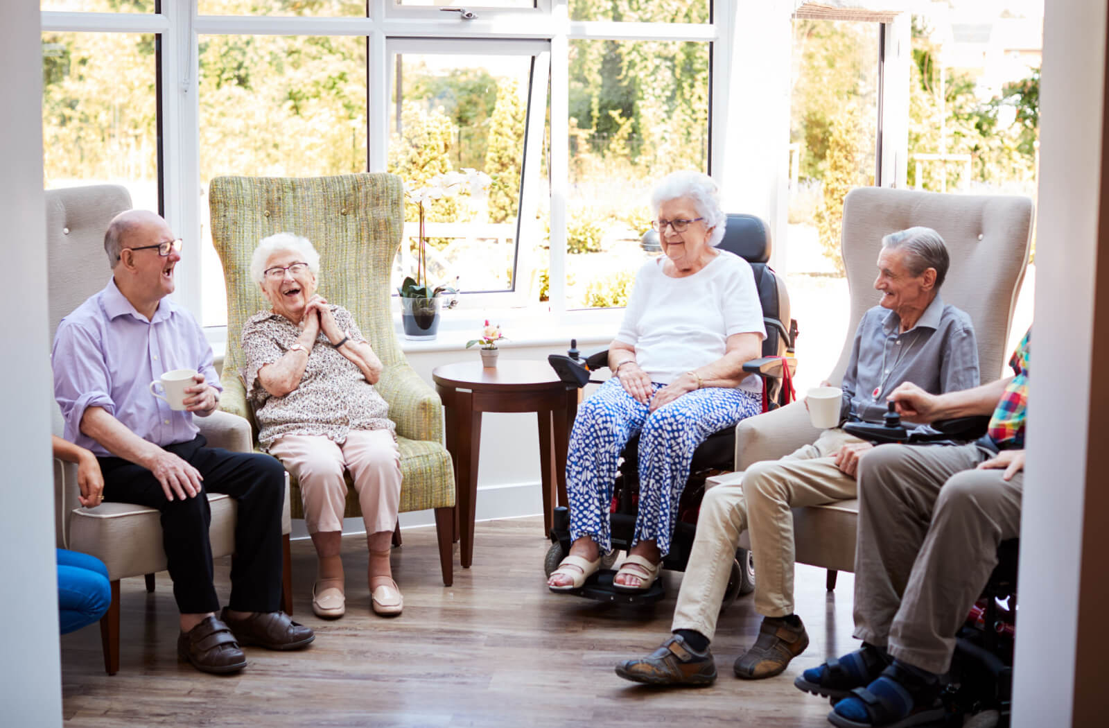 A group of seniors sitting on the chairs chilling and laughing in the lobby of the senior living community