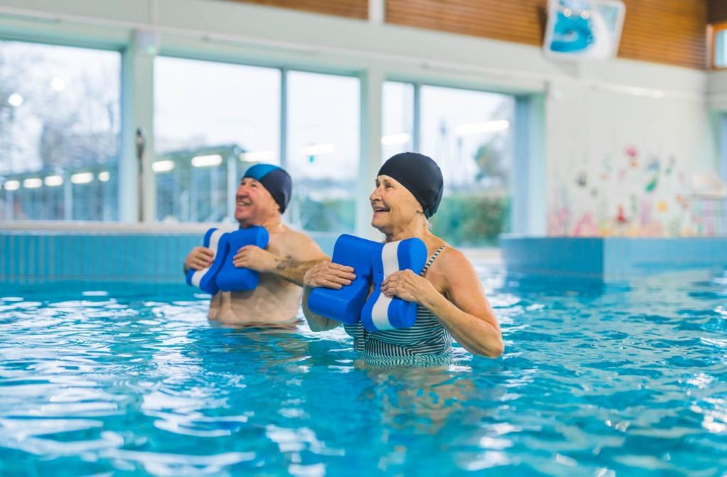 A couple of happy seniors participating in a water aerobics class together.