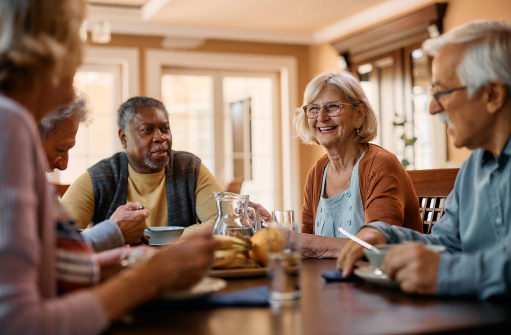 A group of senior friends eating together and socializing in their assisted living community.