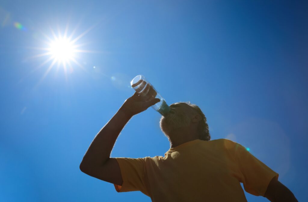 During a warm, blue-skyed summer day, a senior drinks from a water bottle to stay hydrated and cool.