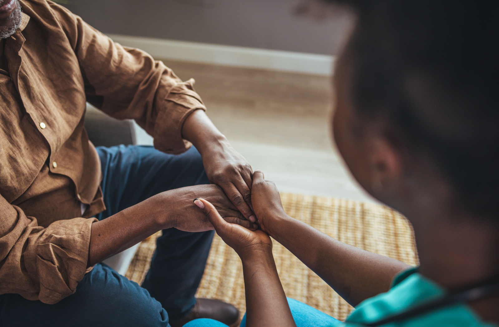 An assisted living staff holding the hands of a resident.