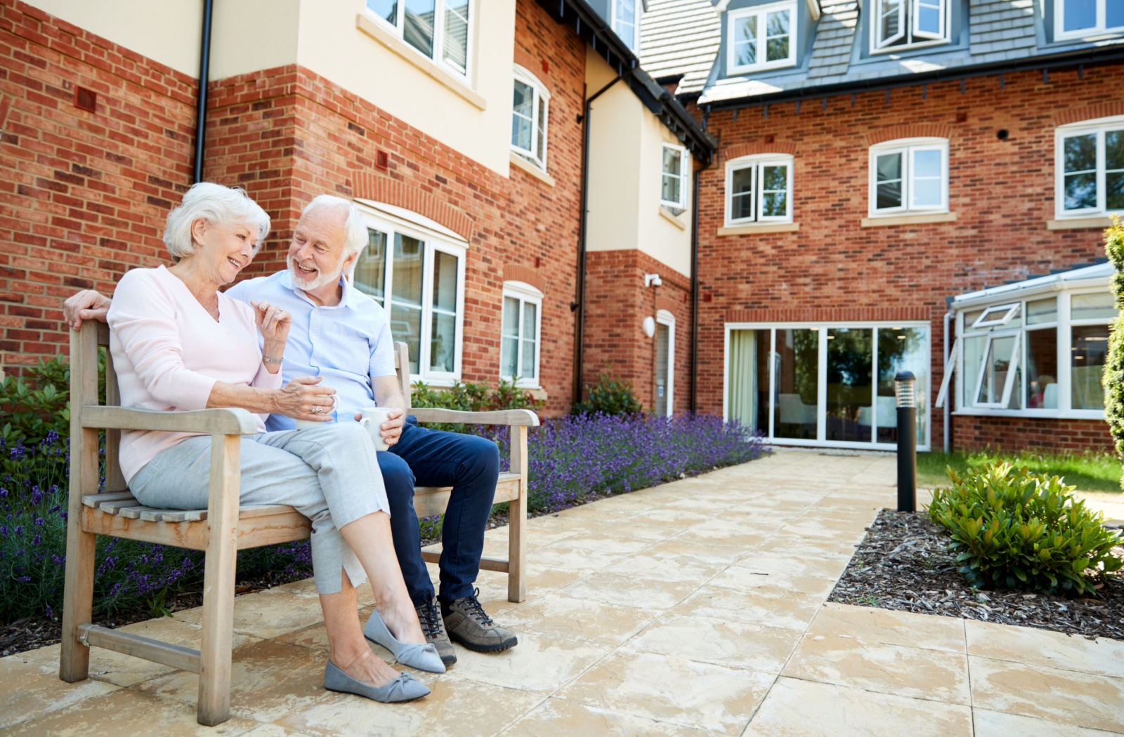 a senior couple sitting and chatting outside of an assisted living community.